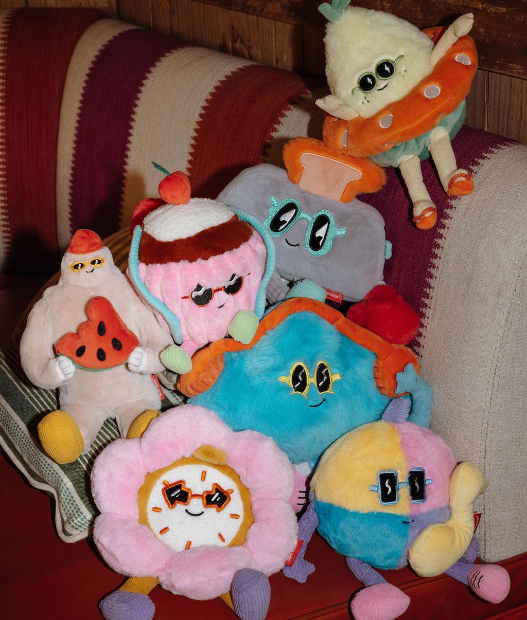Collection de peluches Hello Hossy empilées sur un canapé - photo d'ambiance