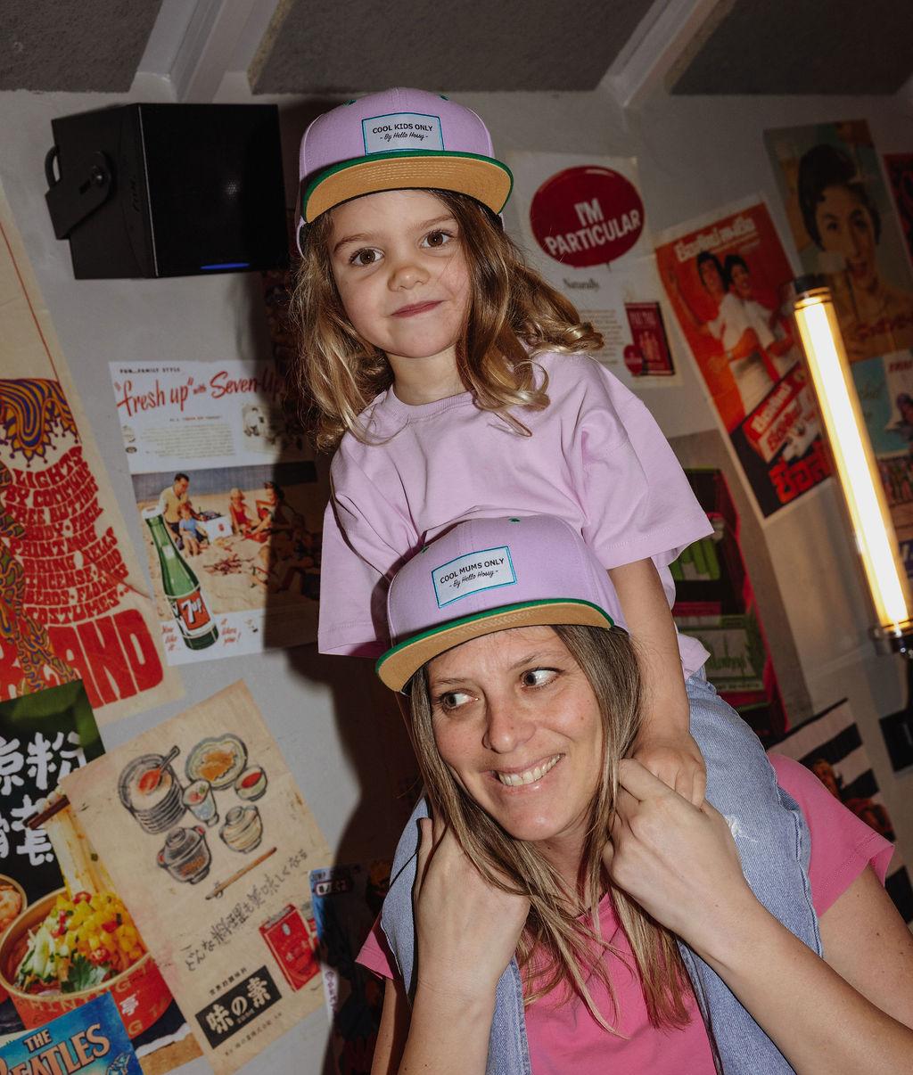 Tweekleurige roze kinderpet en mamapet met groene klep gedragen Hello Hossy