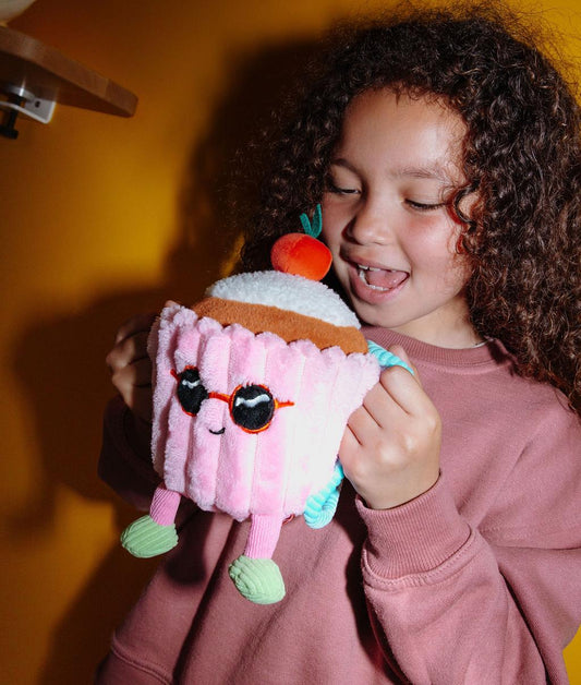 Enfant tenant la peluche douce en forme de gâteau Cherry Cake par les anses de son sac à dos - photo lifestyle - Hello Hossy