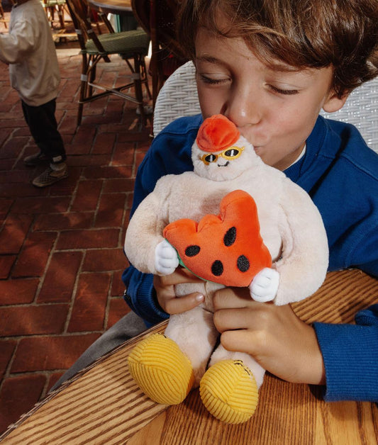 Enfant embrassant la peluche douce en forme de yéti Frosty Yeti posée sur une table en terrasse - photo lifestyle - Hello Hossy