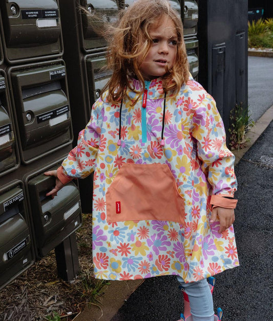 Poncho de pluie imperméable imprimé Retro Flowers avec capuche portée par un enfant - vue de 3/4 - photo lifestyle - Hello Hossy