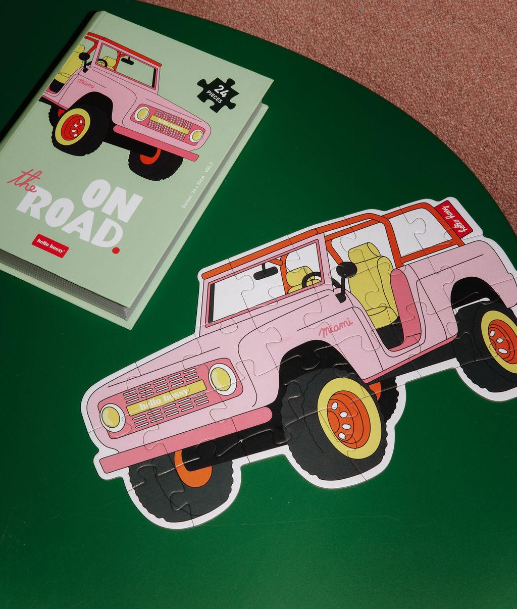 Puzzle coloré "On The Road" assemblé sur une table avec la boîte à côté - vue du dessus - Hello Hossy