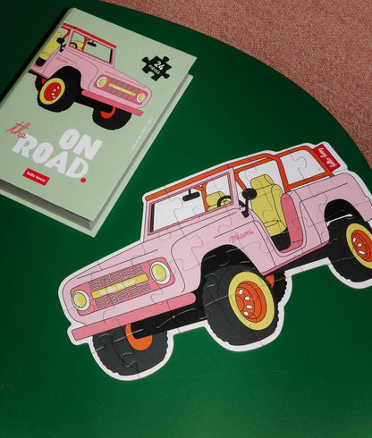 Puzzle coloré "On The Road" assemblé sur une table avec la boîte à côté - vue du dessus - Hello Hossy